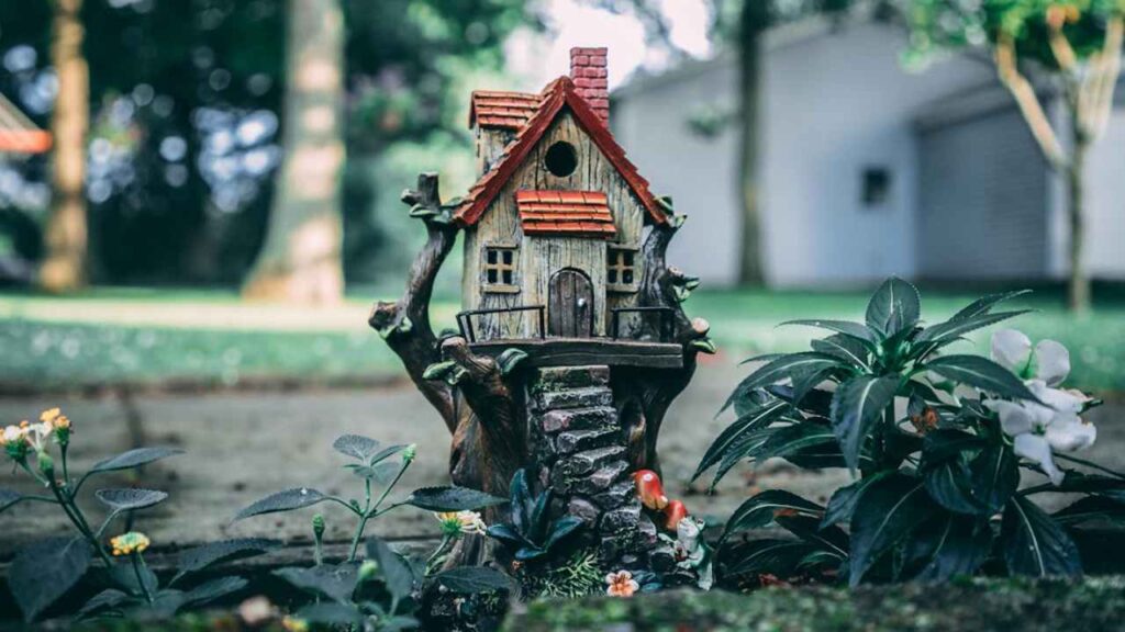 a miniature house sits on top of a tree stump