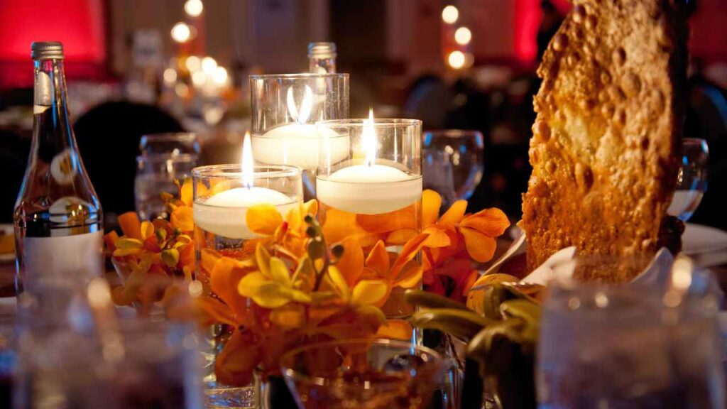 candles are lit in a glass vase on a table