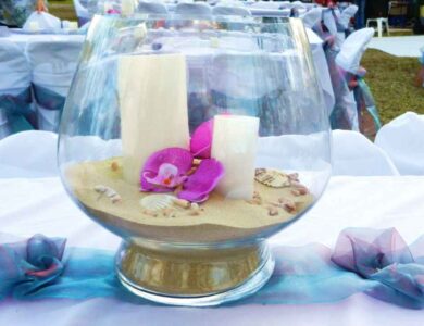 a glass vase filled with sand and flowers on a table