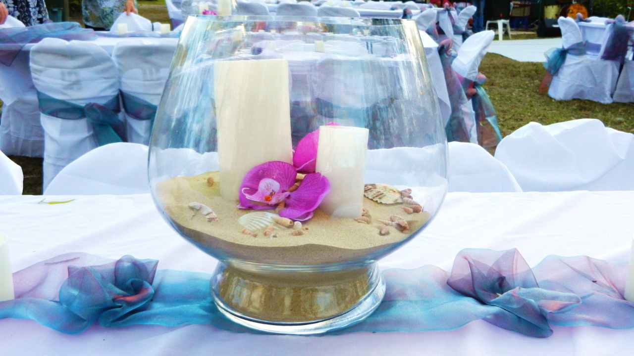 a glass vase filled with sand and flowers on a table