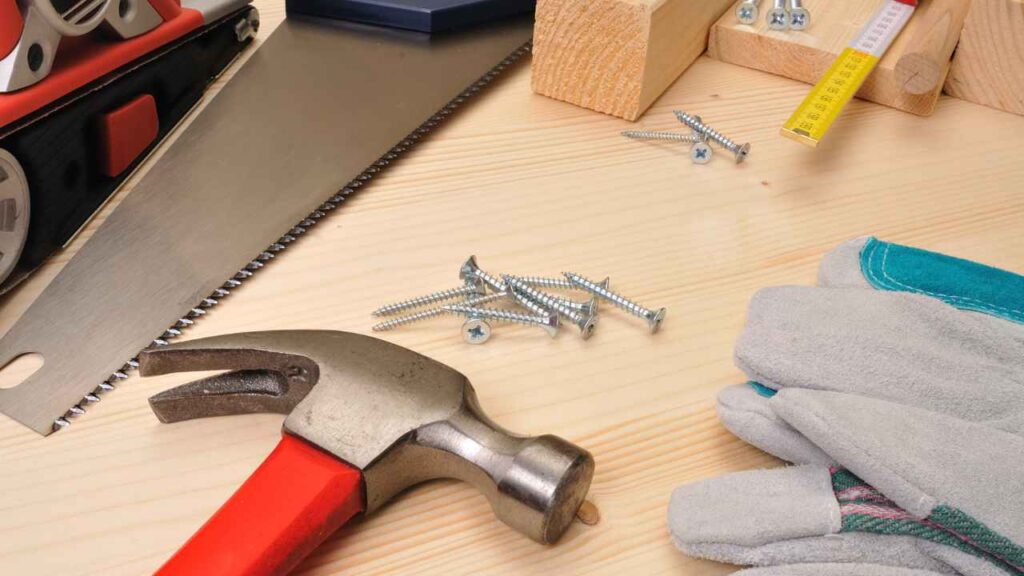 variedtools on a table, including a hammer, pliers, and a pair of gloves