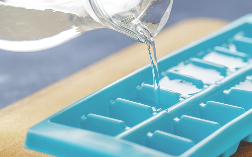 Filling an ice cube tray with clear liquid 