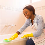 young african woman cleaning bathtub