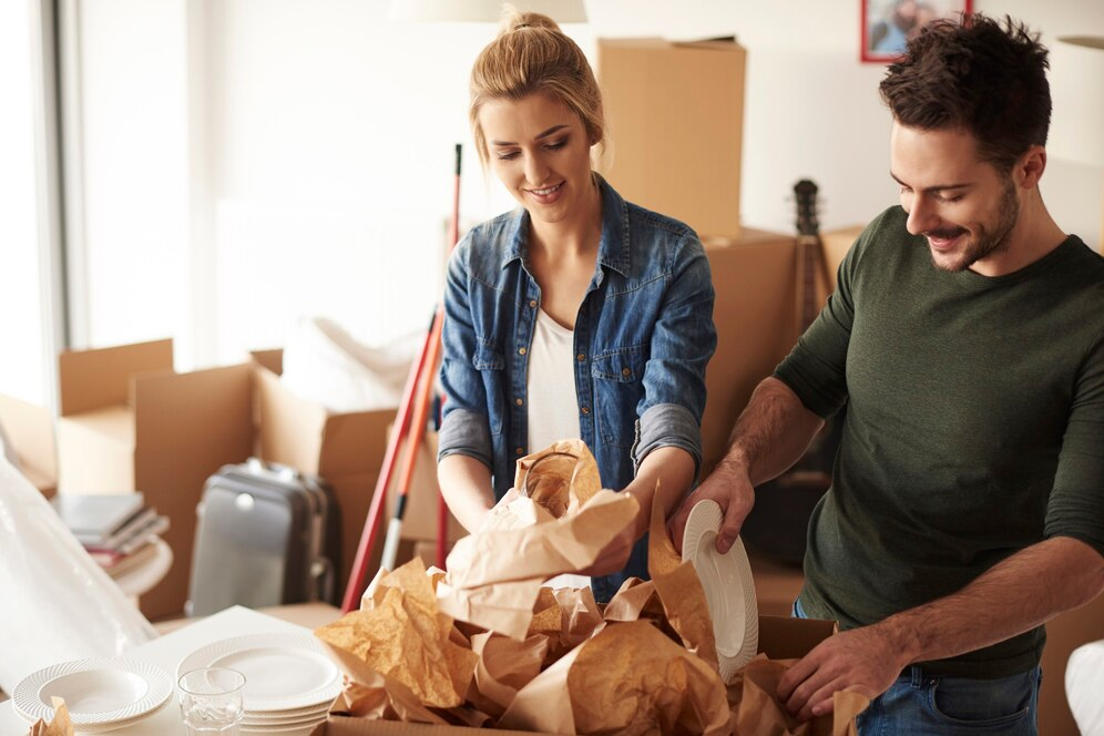 Couple packing cardboard boxes with dishes