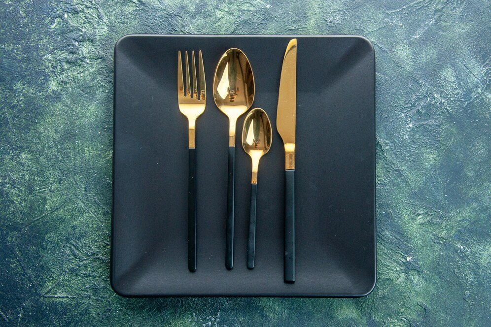 Gold utensils on black plate 