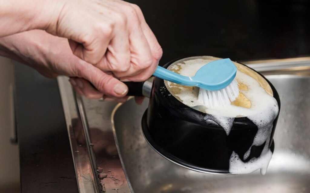 Man scrubbing the bottom of a pot 